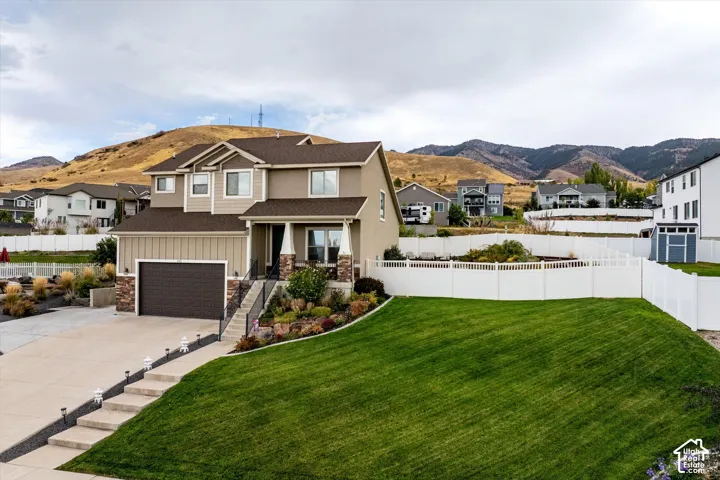 View of front facade with a residential view, a mountain view, board and batten siding, concrete driveway, and a porch