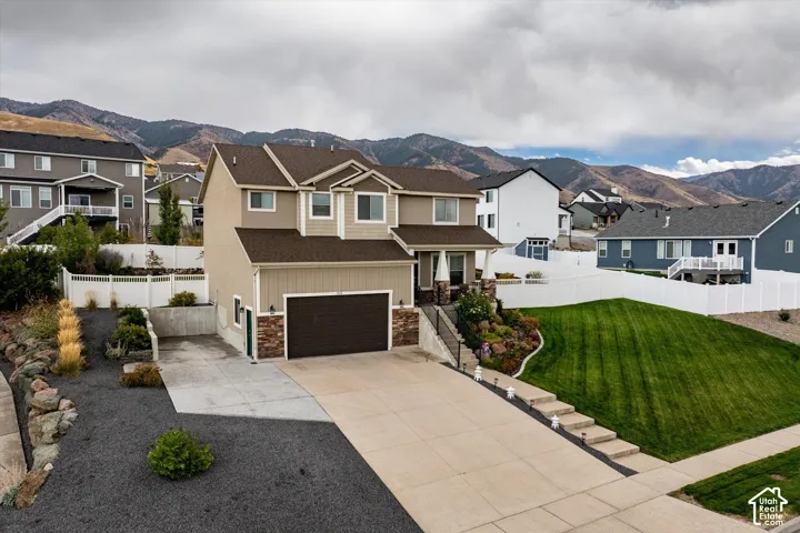 View of front of house with a mountain view, a residential view, driveway, and an attached garage