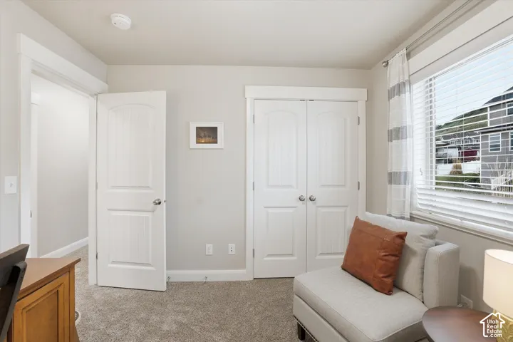 Living area featuring baseboards and light carpet
