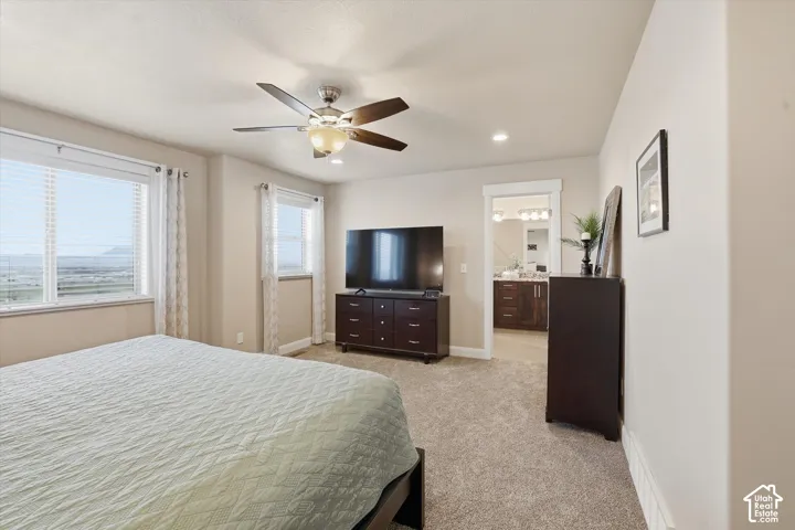 Bedroom with light colored carpet, ceiling fan, recessed lighting, and connected bathroom