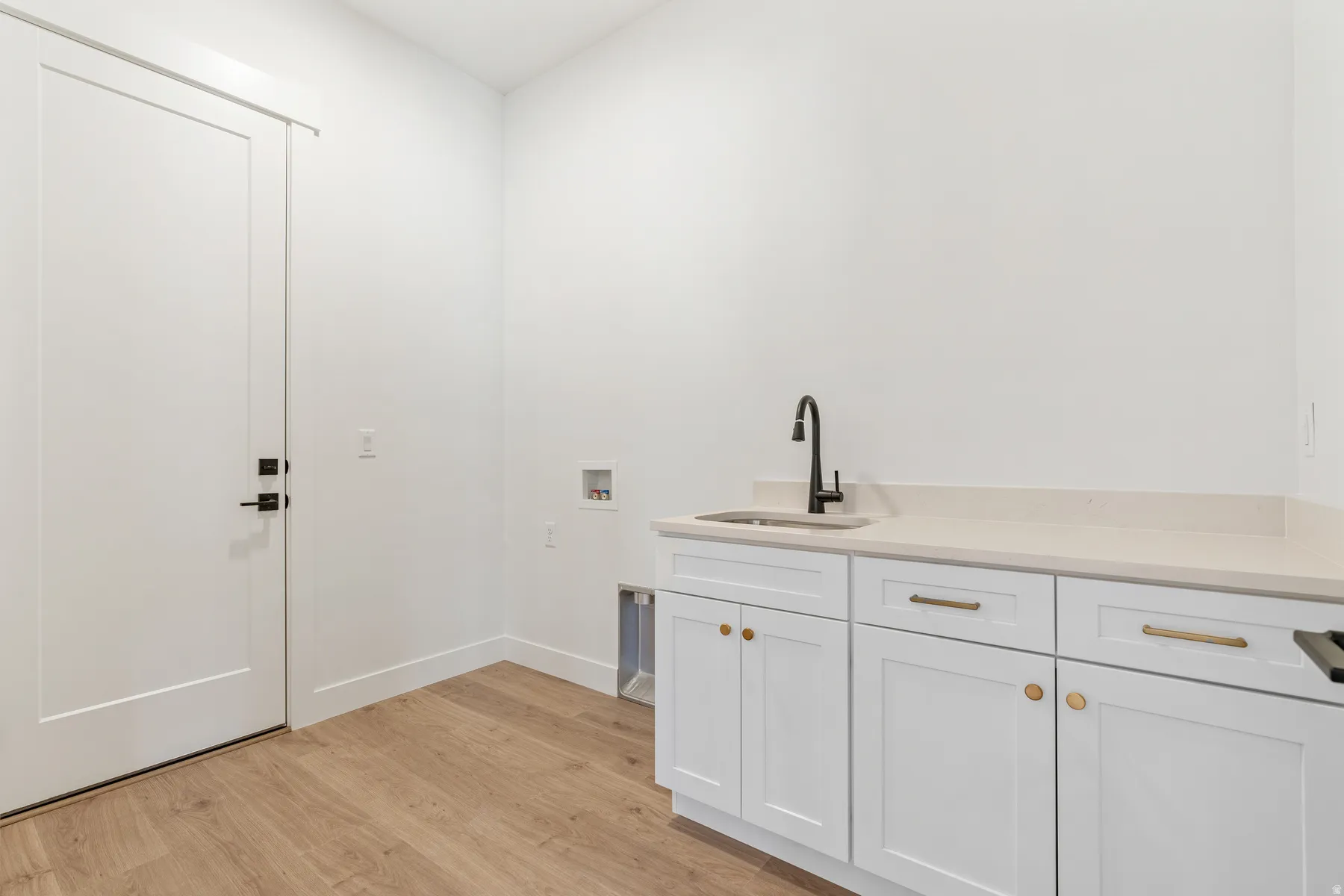 Laundry area featuring light wood-style floors, washer hookup, and cabinet space