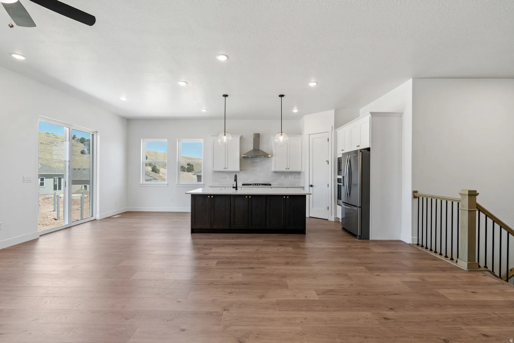 Kitchen featuring light countertops, open floor plan, a center island with sink, pendant lighting, and dual tone cabinetry