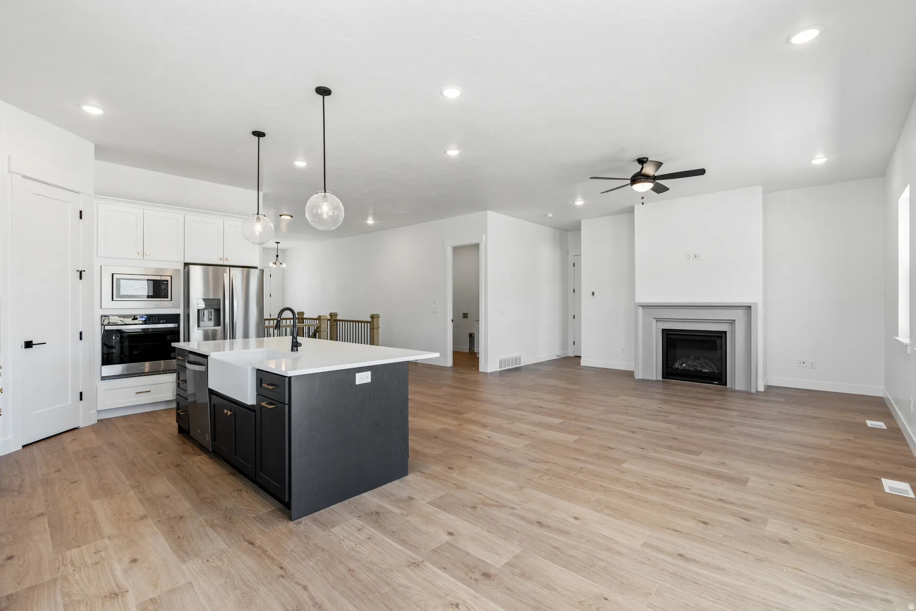 Kitchen featuring open floor plan, hanging light fixtures, an island with sink, stainless steel appliances, and two tone cabinets