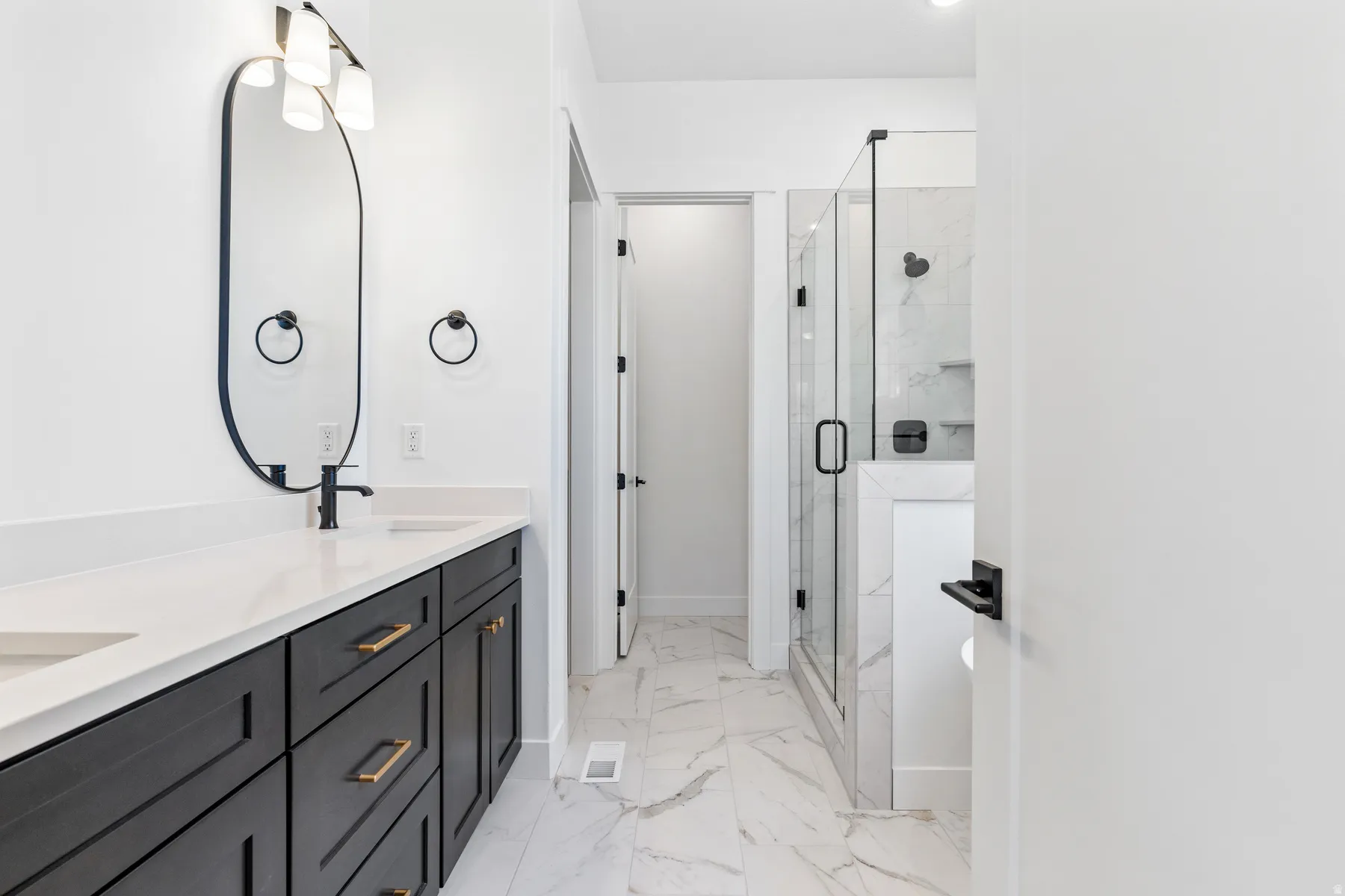 Full bathroom with double vanity, a marble finish shower, and light marble finish floors