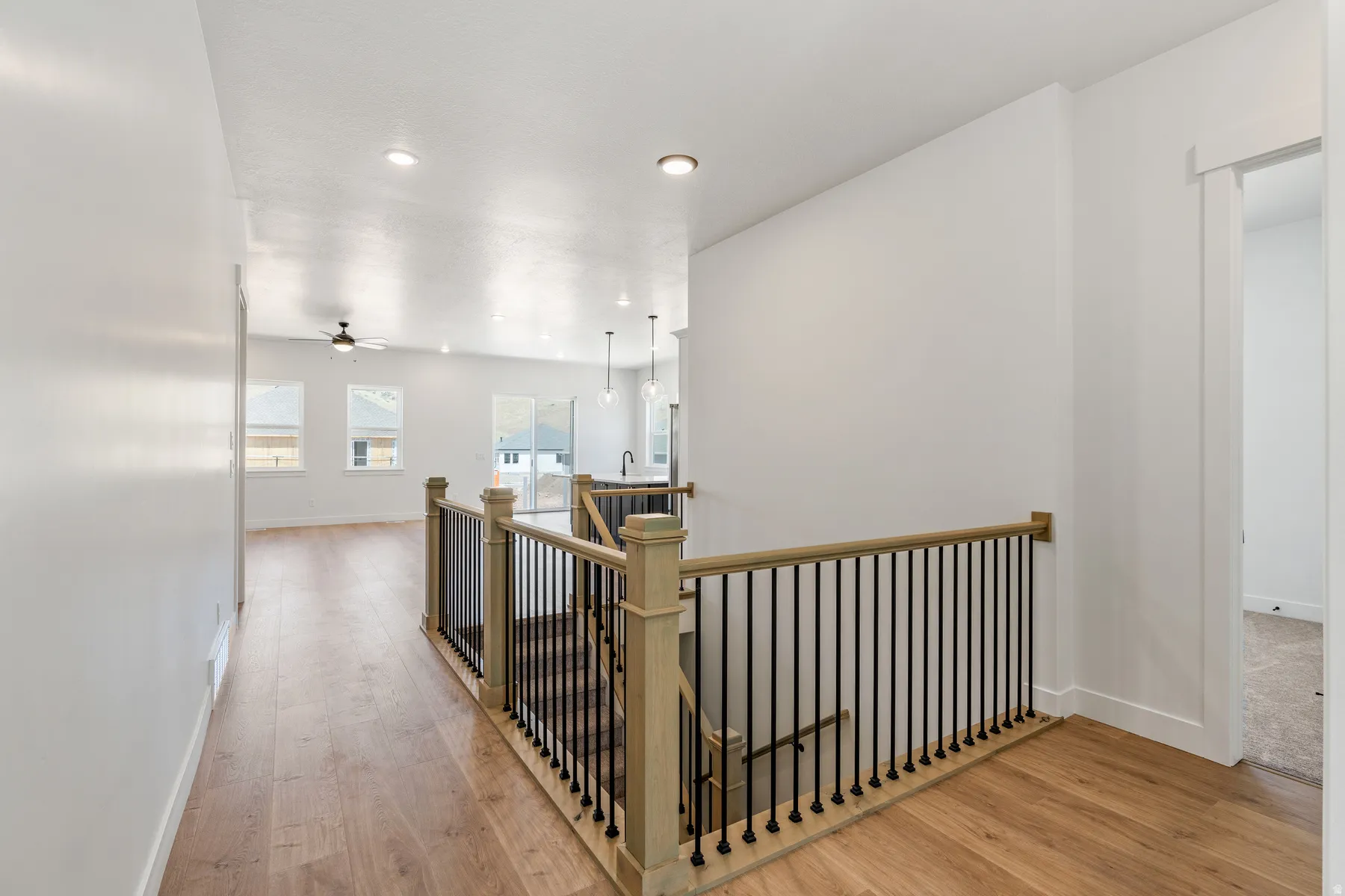 Hallway with light wood-style flooring, an upstairs landing, and recessed lighting