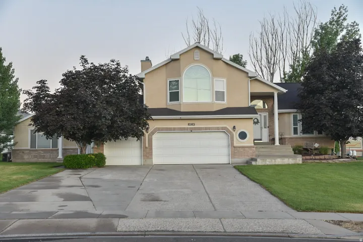 View of front of house featuring a front lawn, stucco siding, driveway, an attached garage, and a chimney