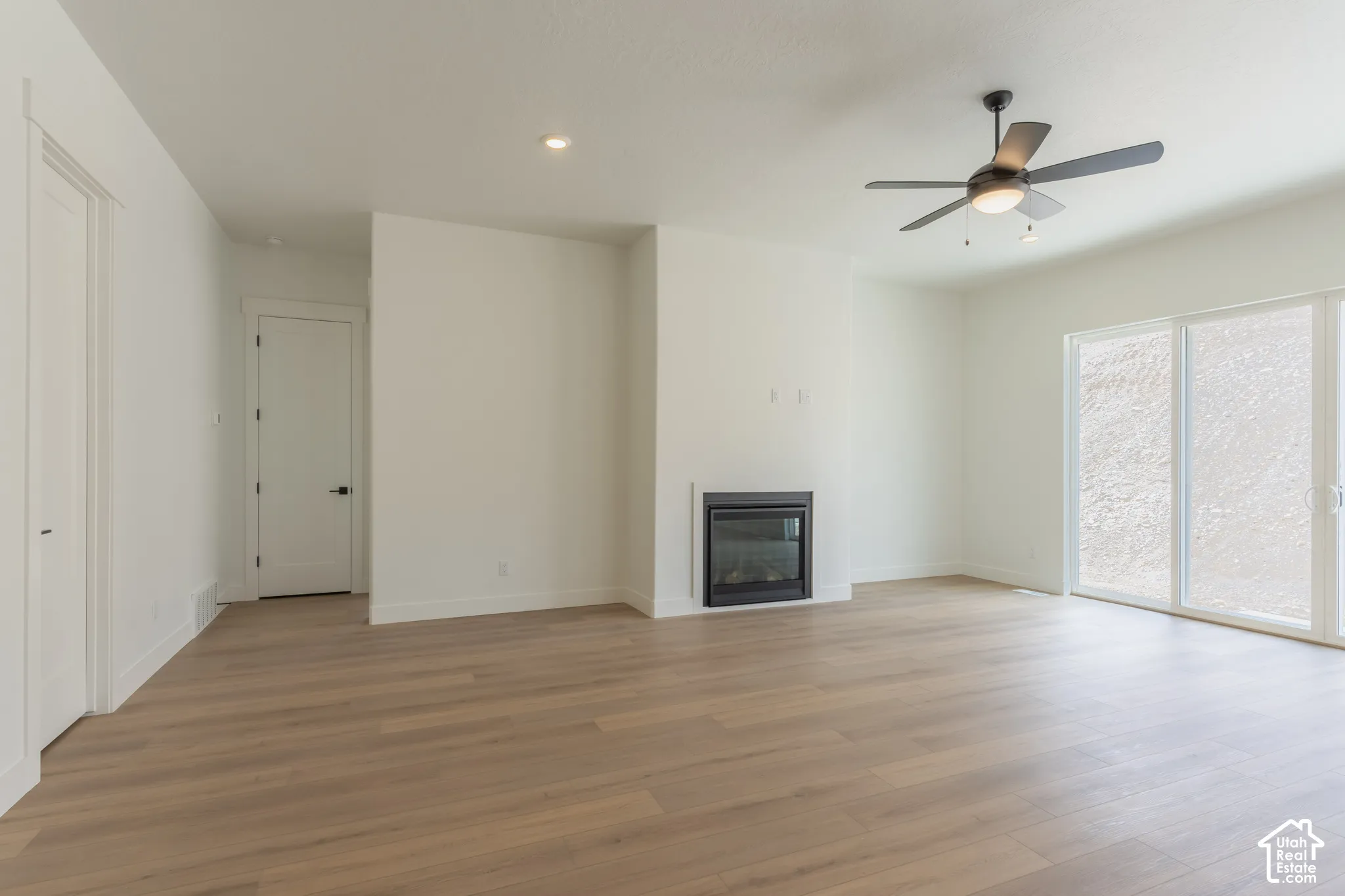 Spacious room featuring wood-finish flooring, a built-in fireplace, a ceiling fan with integrated lighting, recessed lighting, and sliding glass doors
