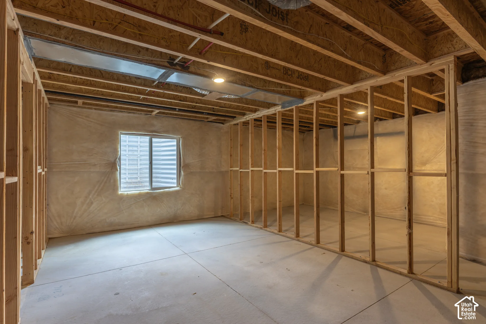 Unfinished basement with exposed ceiling joists, concrete flooring, and framed interior walls