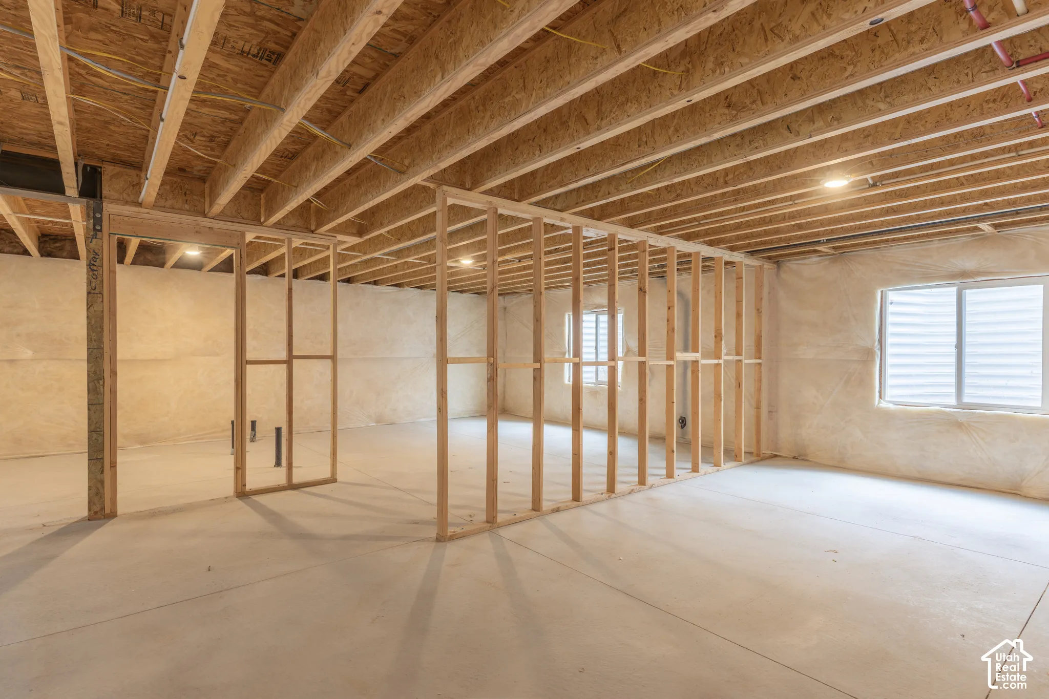 Concrete flooring, exposed wood ceiling joists, framed interior walls, recessed lighting, and dual window openings
