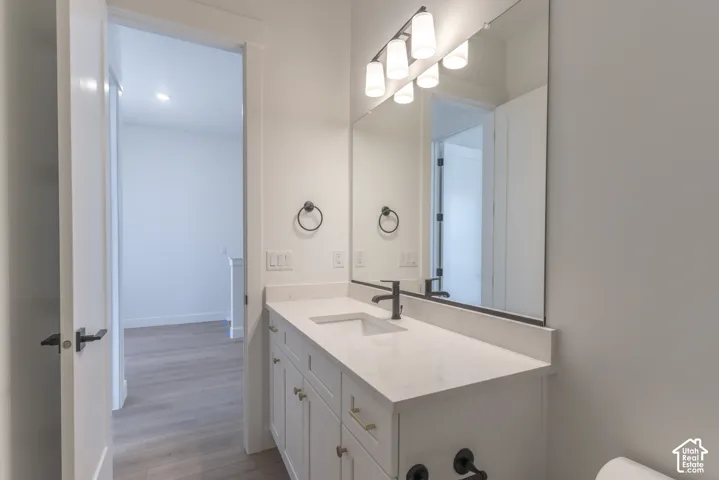 White vanity with integrated sink, stone countertop, matte black faucet, and rectangular mirror with overhead lighting