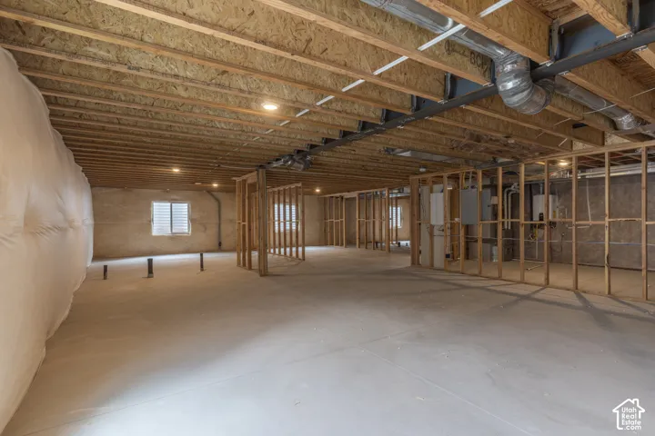 Unfinished basement with concrete flooring, exposed wood ceiling joists, and recessed lighting