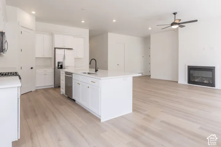 Kitchen with white cabinetry, stainless steel appliances, and a central island with a sink