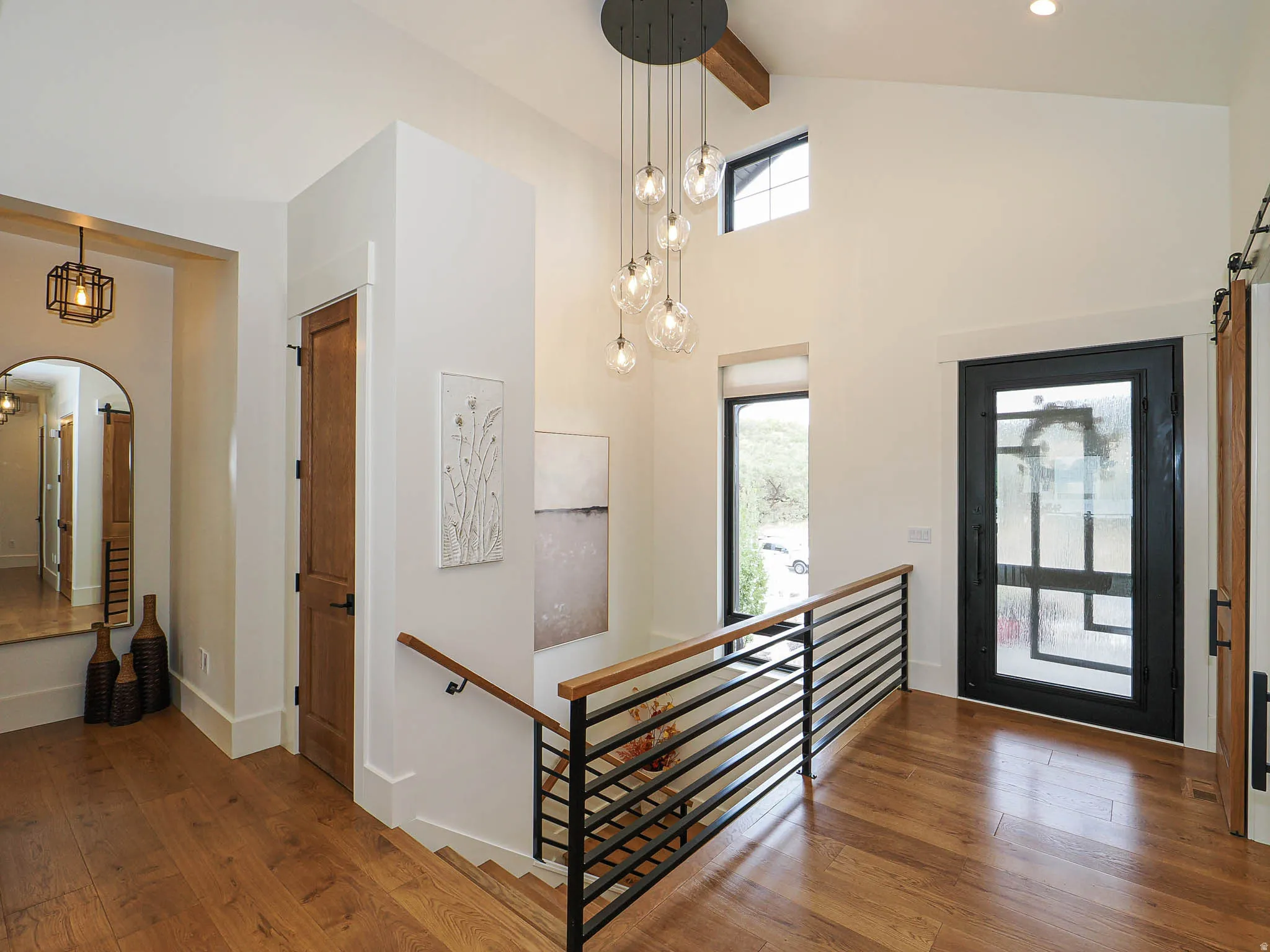Foyer entrance with hardwood / wood-style flooring, arched walkways, a barn door, and lofted ceiling