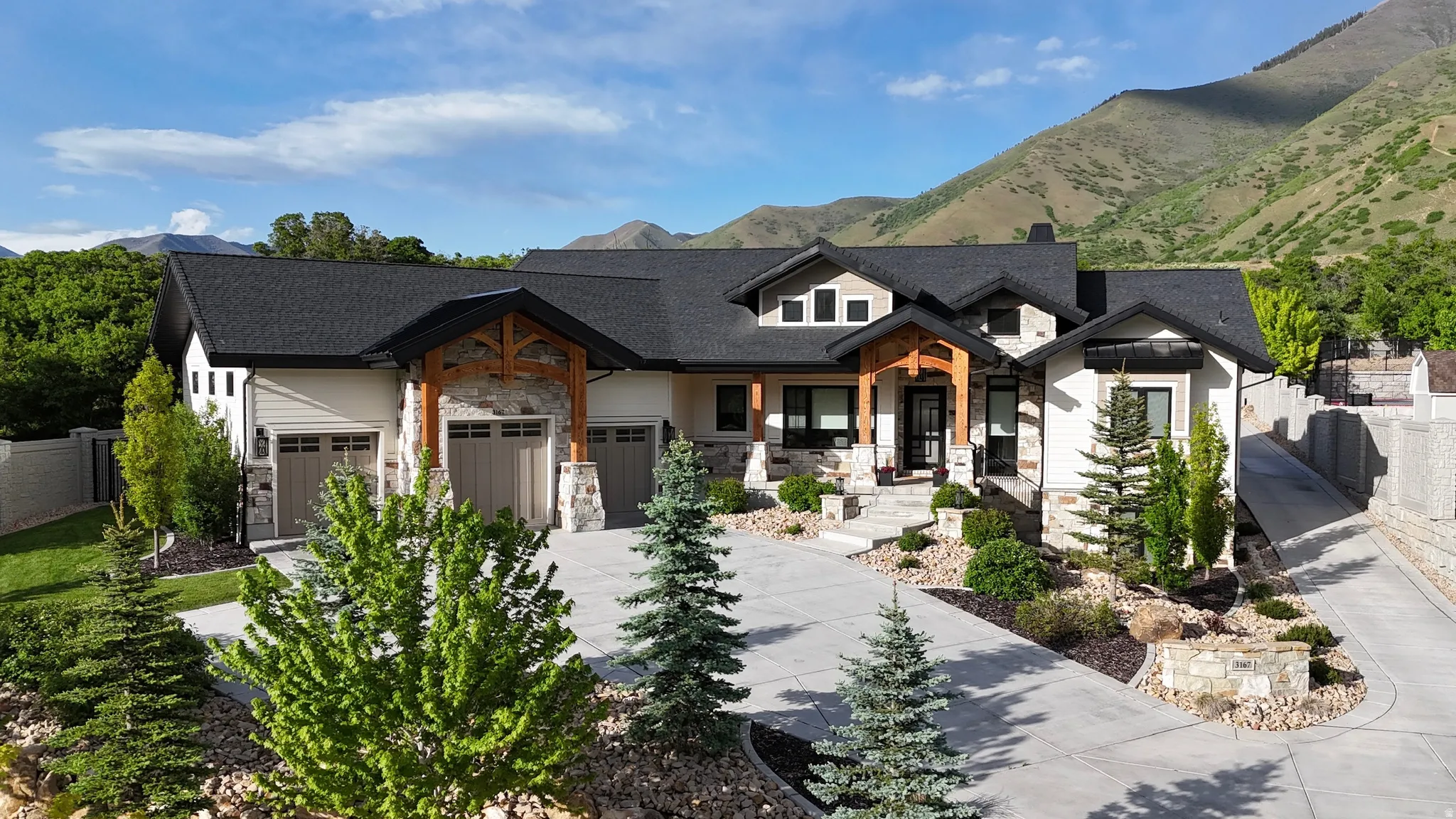 Modern inspired farmhouse with stone siding, driveway, a garage, a mountain view, and a chimney