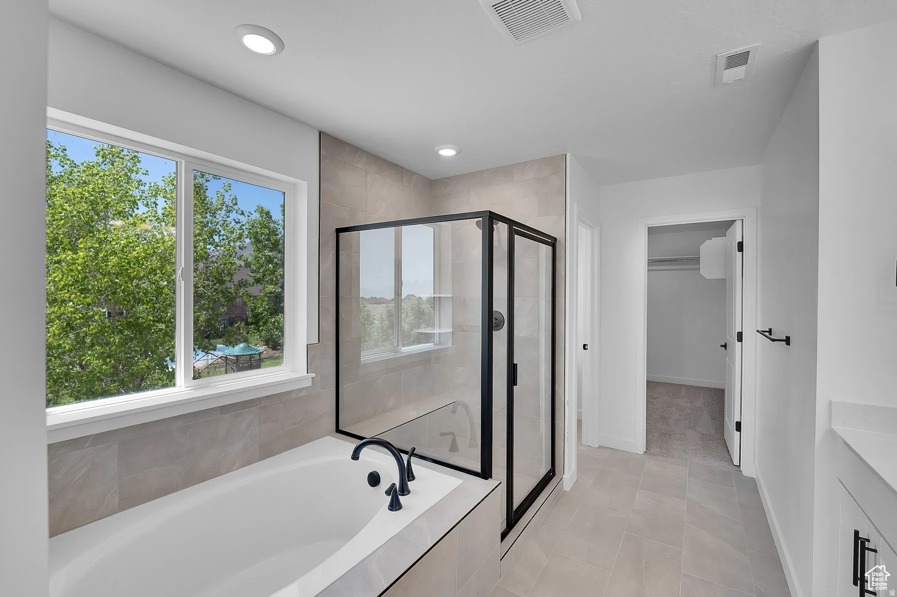 *Colors may vary** Full bath with a garden tub, a stall shower, vanity, a spacious closet, and light tile patterned floors