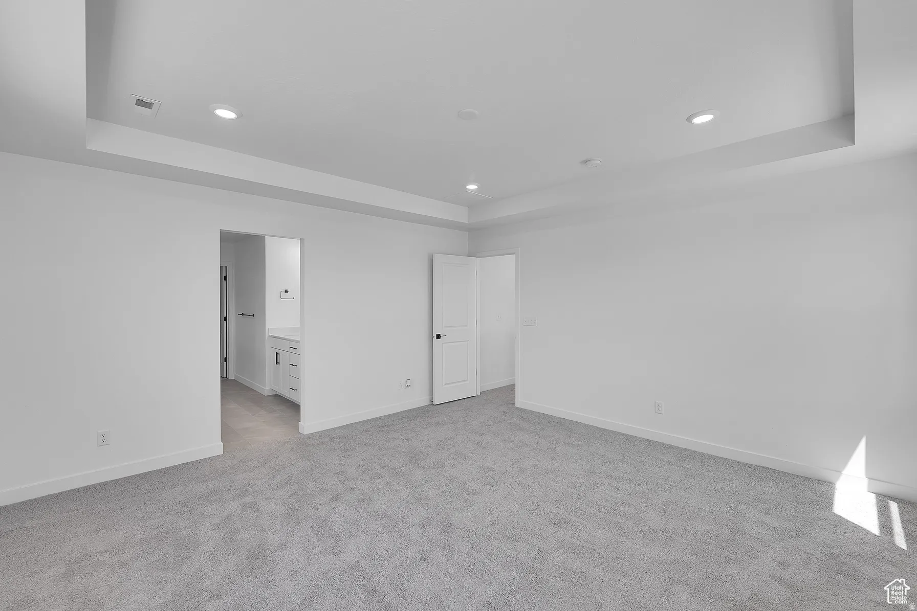 *Colors may vary** Primary bedroom with a tray ceiling, light colored carpet, ensuite bath, and recessed lighting