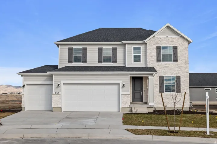 *Colors may vary** Traditional-style house with driveway, stone siding, an attached garage, and a shingled roof