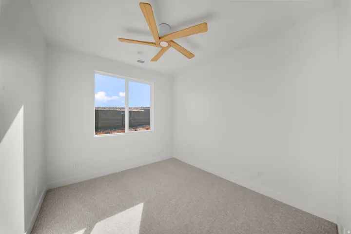 Empty room featuring carpet and a ceiling fan