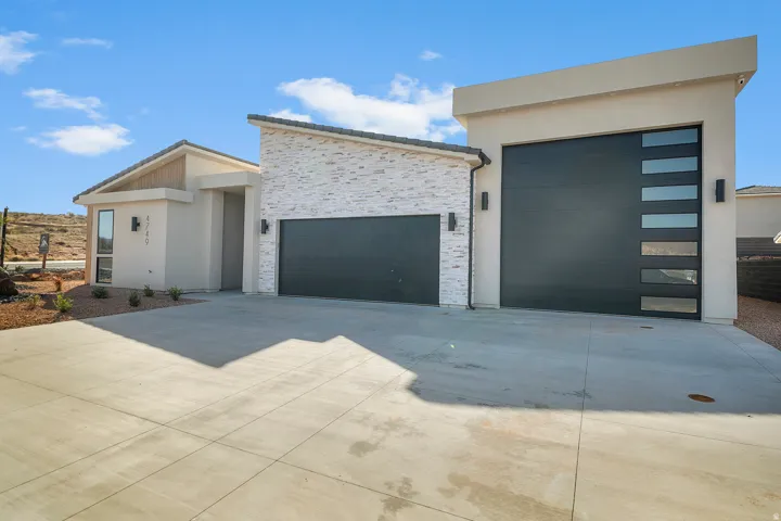 Contemporary home with concrete driveway, a garage, stucco siding, and stone siding