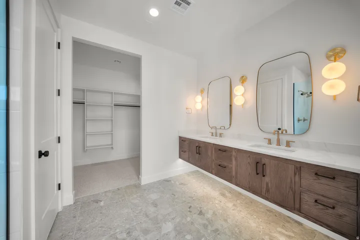 Bathroom featuring a walk in closet, double vanity, and recessed lighting