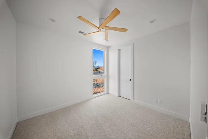 Spare room with light carpet and a ceiling fan