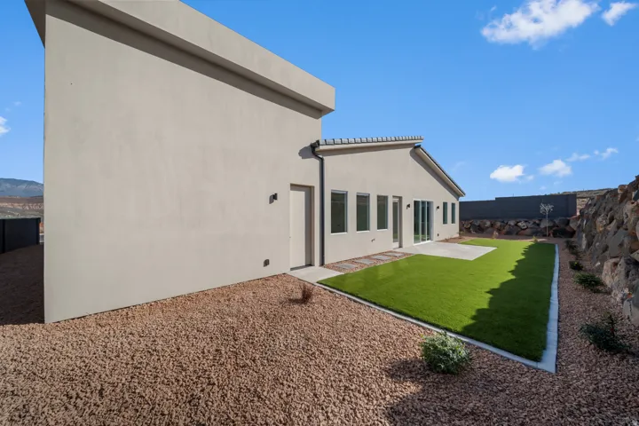 Rear view of property with stucco siding, a fenced backyard, and a patio