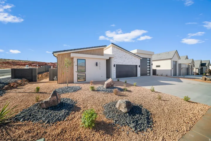 Contemporary house with an attached garage, driveway, and stone siding