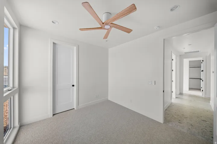 Carpeted empty room featuring a ceiling fan and baseboards