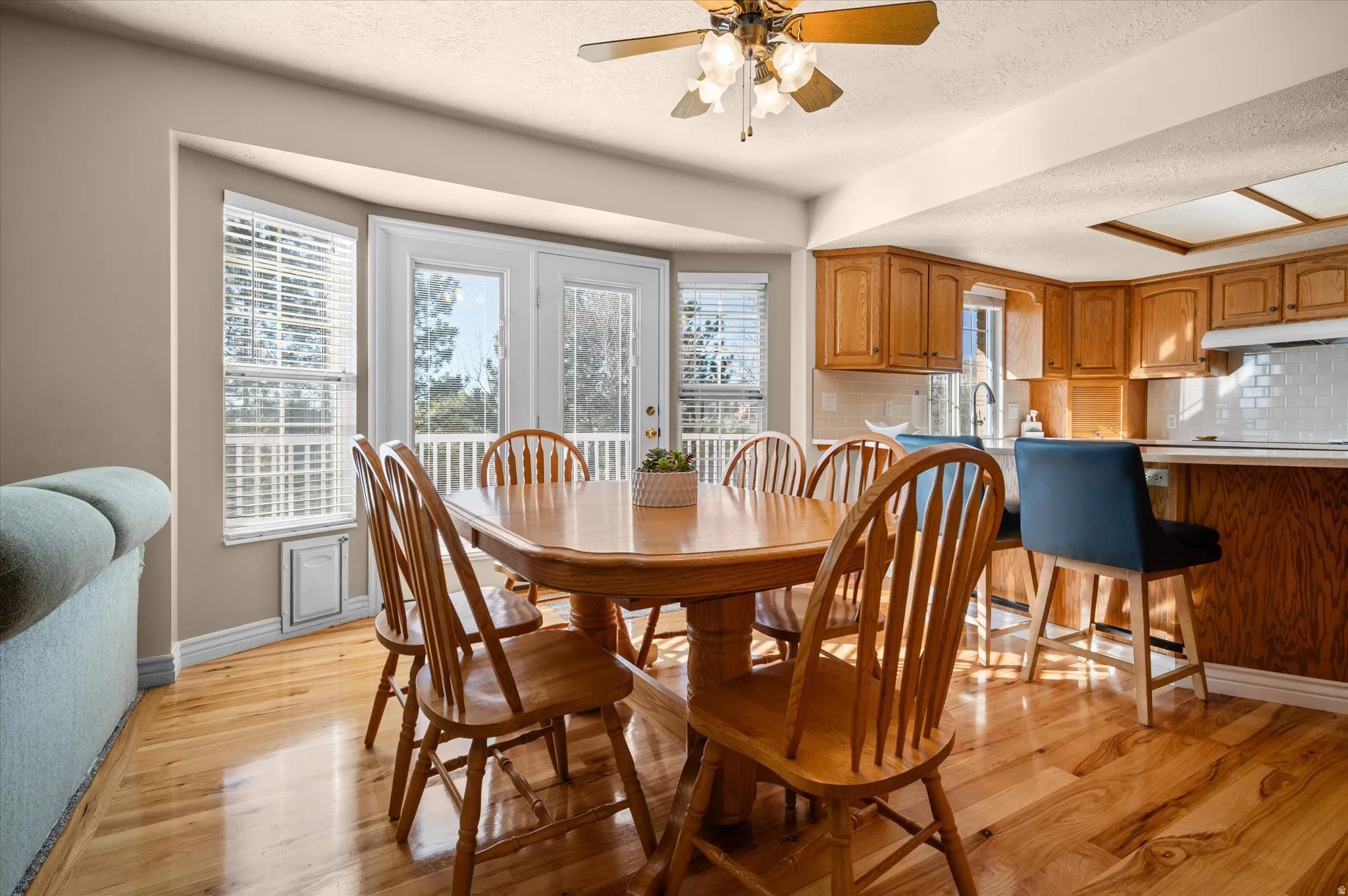 Dining area featuring ceiling fan, light wood-style flooring, and a textured ceiling