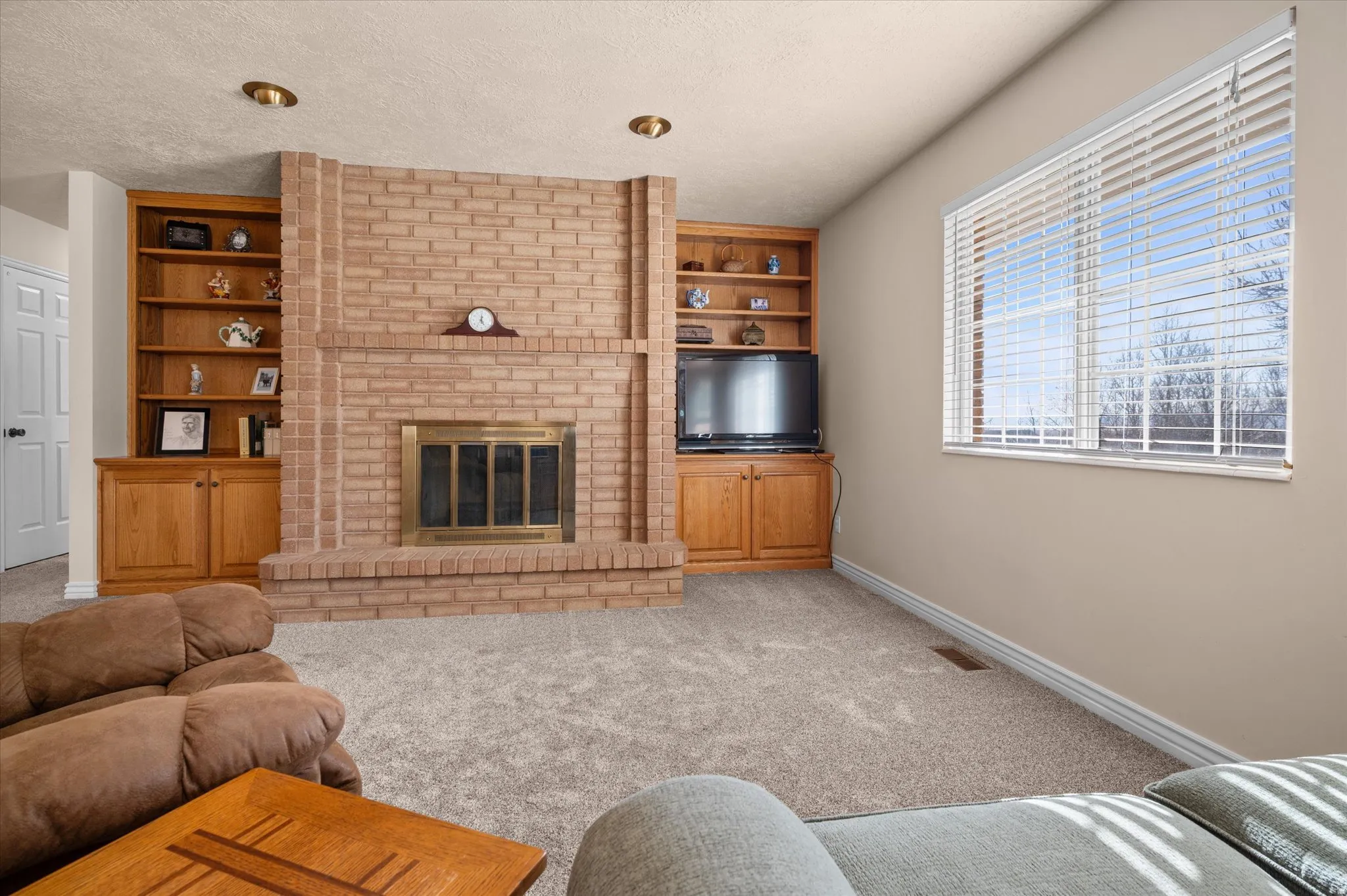 Carpeted living area with a fireplace, built in shelves