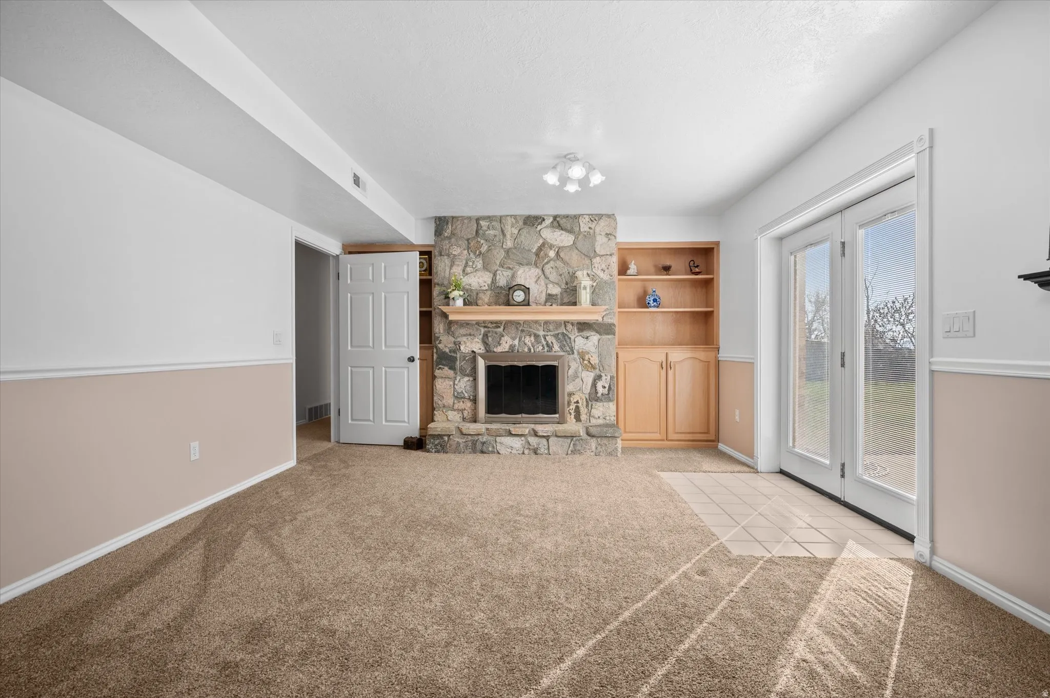 Living room featuring a stone fireplace, light carpet, and built in shelves