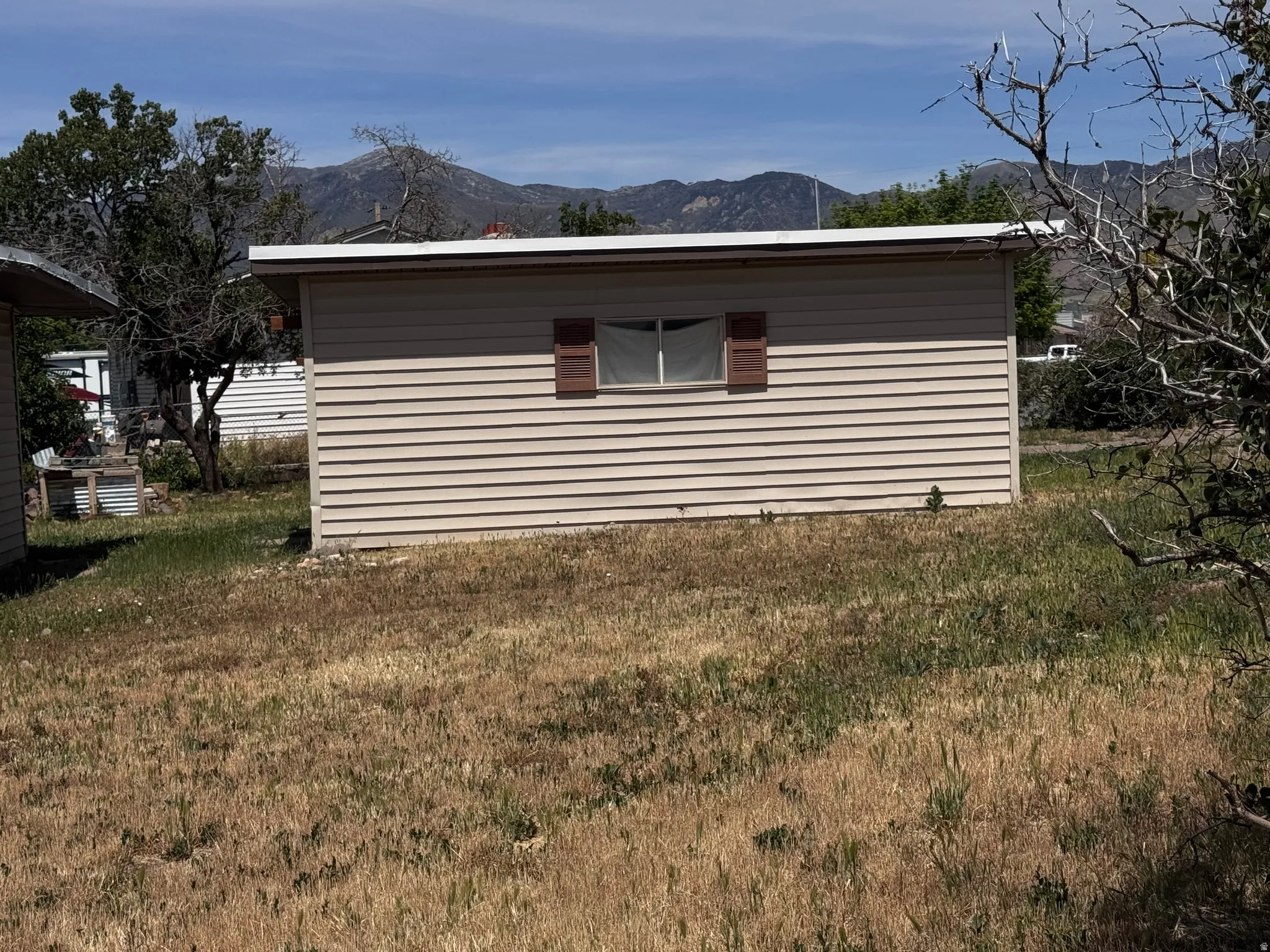 Single-story structure with horizontal siding, a single window with decorative shutters, and a flat roofline