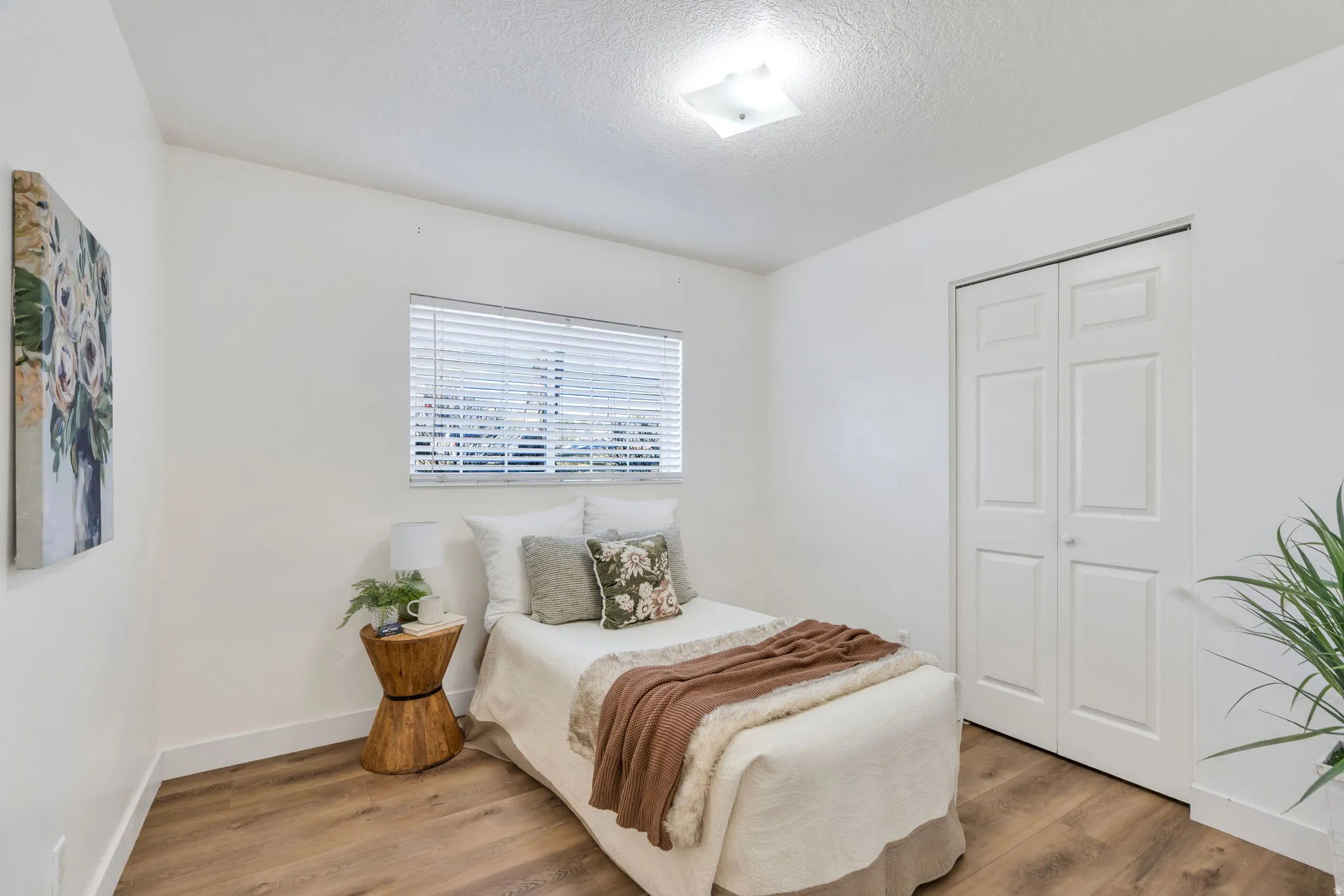 Bedroom with wood finished floors, a closet, and a textured ceiling