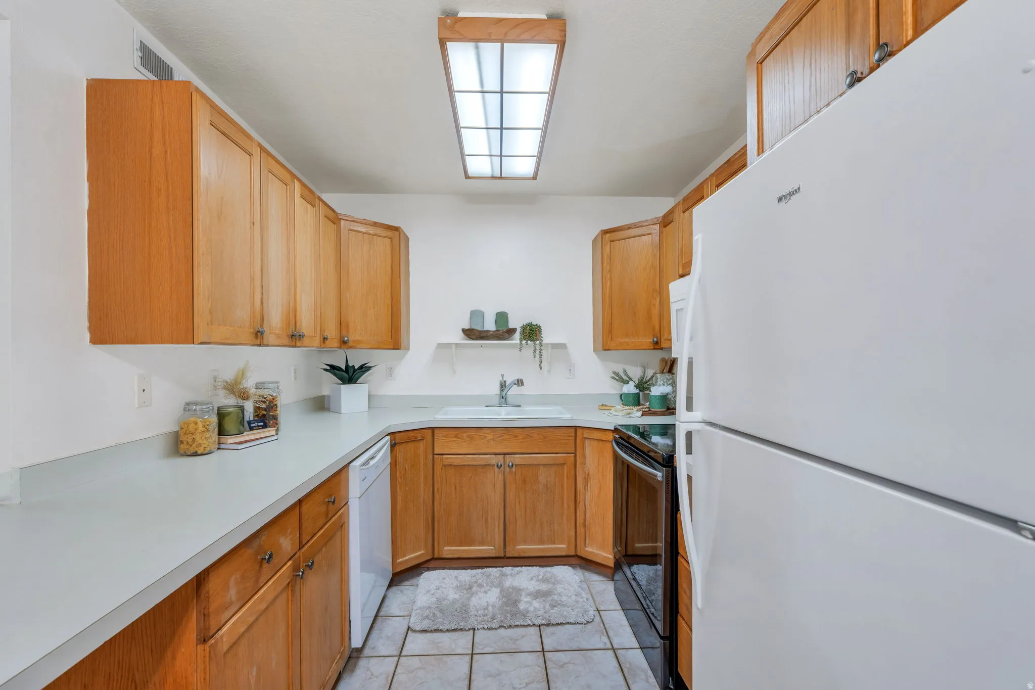 Kitchen featuring white appliances, light countertops, open shelves, and wood finish cabinets