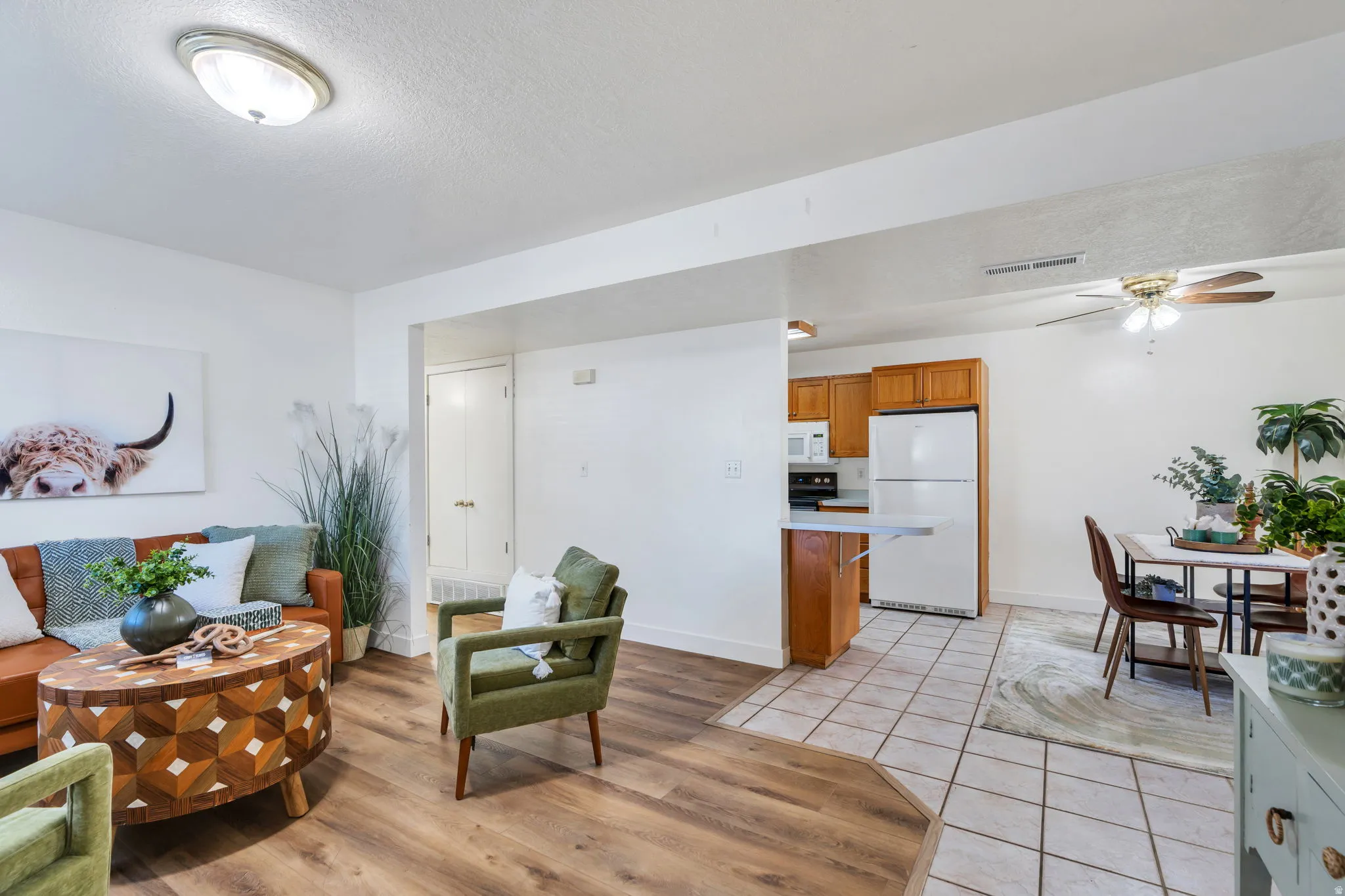 Living area featuring light tile patterned floors, ceiling fan, and a textured ceiling