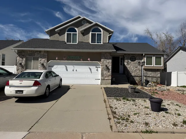 View of front of house featuring stone siding, driveway, and stucco siding