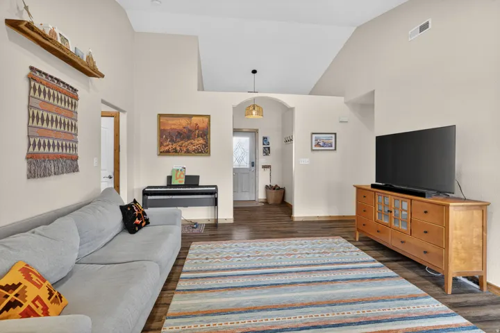 Living area with dark wood finished floors, vaulted ceiling, and arched walkways
