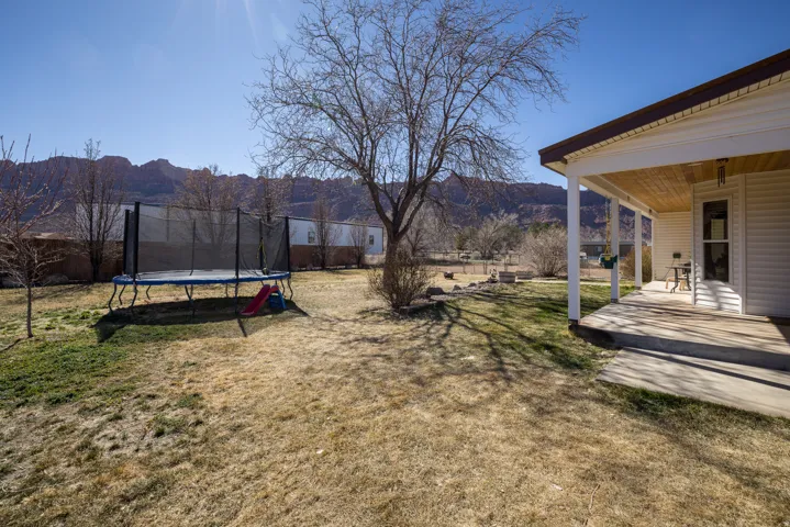 Fenced yard with a patio, a trampoline, and a mountain view