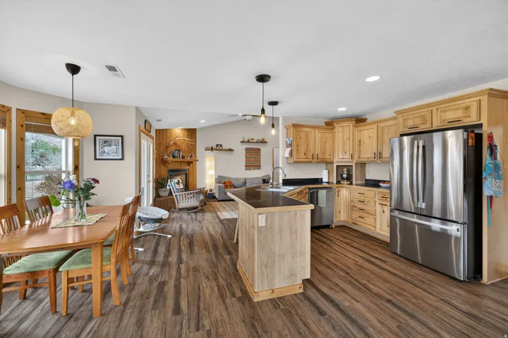 Kitchen with a peninsula, light wood finish cabinets, stainless steel appliances, open floor plan, and a large fireplace