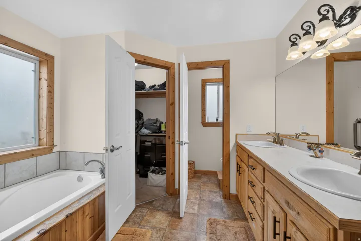 Bathroom with a garden tub, stone finish flooring, and double vanity