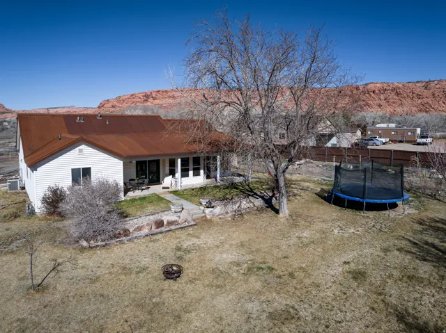Rear view of property with a mountain view, a fire pit, a patio, and a trampoline