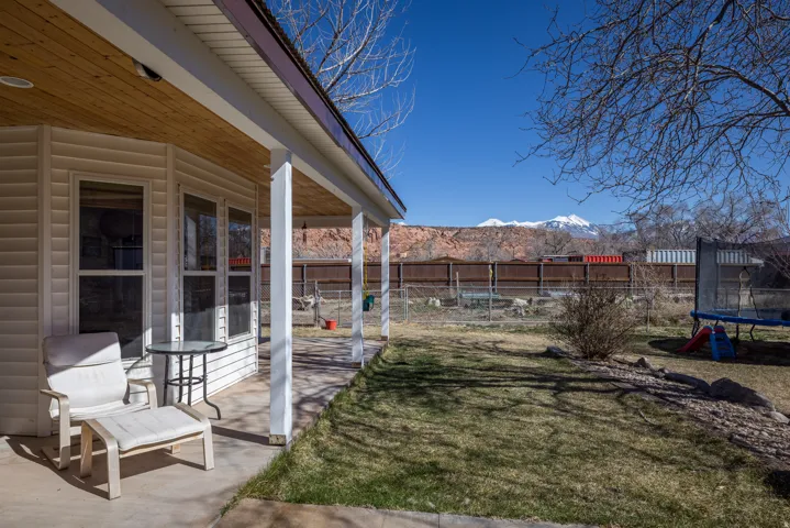 Fenced backyard featuring a mountain view, a trampoline, and a patio
