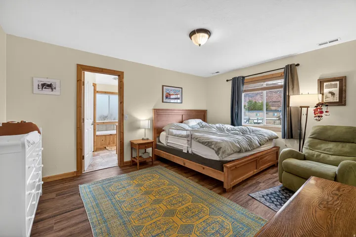 Bedroom with dark wood finished floors and ensuite bath