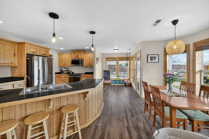 Kitchen featuring tile countertops, stainless steel appliances, dark wood-style flooring, and pendant lighting