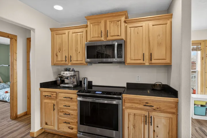 Kitchen with stainless steel appliances, dark wood-style flooring, and light wood finish cabinets