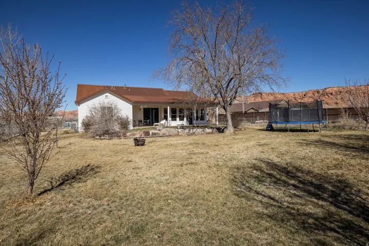 Rear view of house with a fenced backyard, a patio area, and a trampoline
