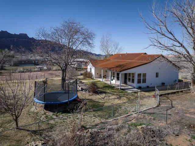 Rear view of property with a patio area, a fenced backyard, a trampoline, and a mountain view