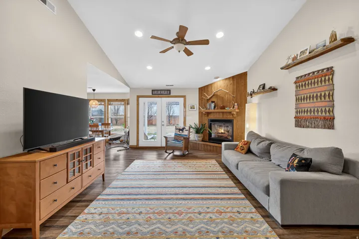 Living room featuring lofted ceiling, ceiling fan, a fireplace, recessed lighting, and dark wood-style floors