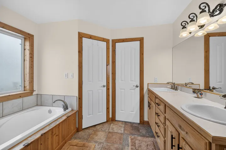 Full bathroom featuring stone finish flooring, double vanity, and a garden tub