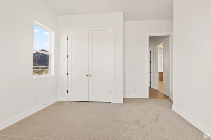 Unfurnished bedroom with light carpet and a closet